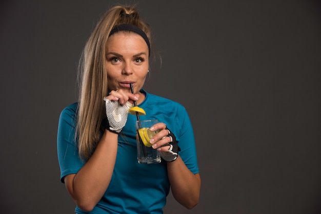 Young sportive woman having energy drink with pipe. 