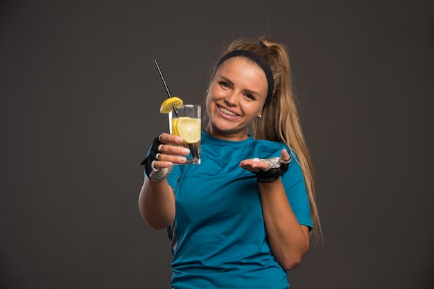 Молодая спортивная женщина, предлагающая воду с лимоном.