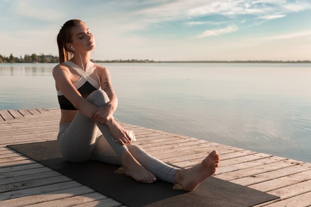 Young sports lady at the beach listening music with earphones.