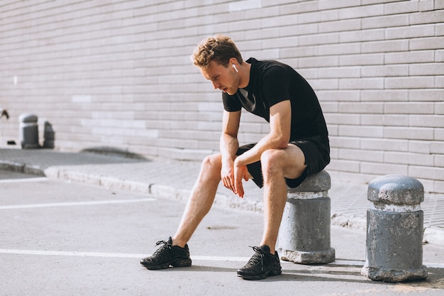 Young sports man stopped to sit