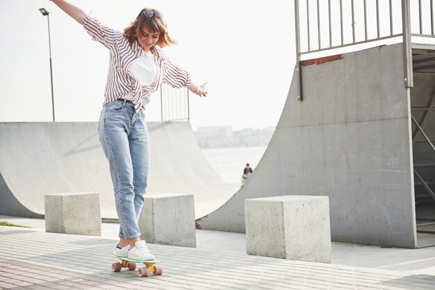 Молодая спортивная женщина, которая катается в парке на скейтборде.