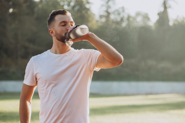 Young sportsman drinking water at stadium