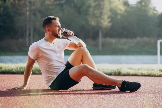 Young sportsman drinking water at stadium