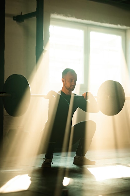 Young sportsman exercising with barbell on cross training in a gym