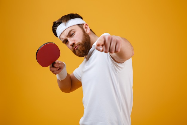 Young sportsman holding racket for table tennis while pointing.