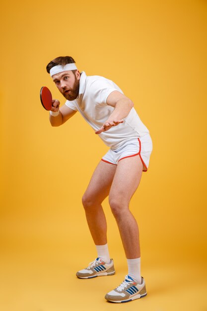 Молодой спортсмен держит ракетку для настольного тенниса.