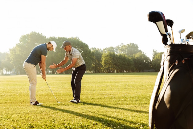 Молодой спортсмен практикует гольф со своим учителем