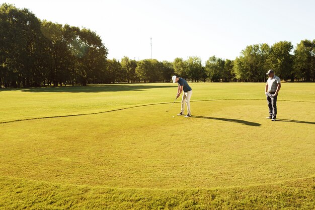 Молодой спортсмен практикует гольф со своим учителем