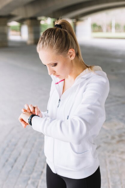 Young sportswoman checking smartwatch