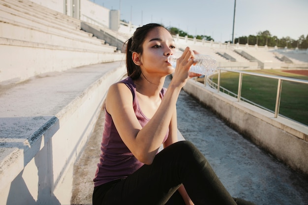 Young sportswoman drinking water