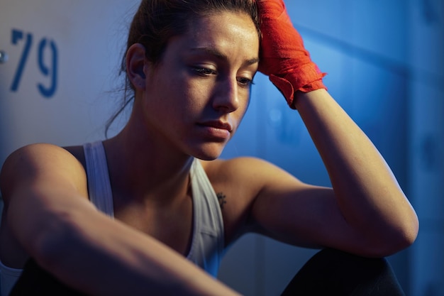 Young sportswoman not feeling motivated while sitting in gym's dressing room before sports training