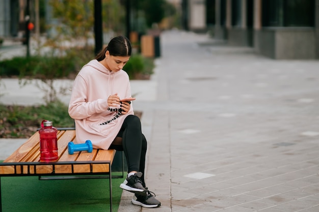 Young sportswoman sitting on the bench at the park