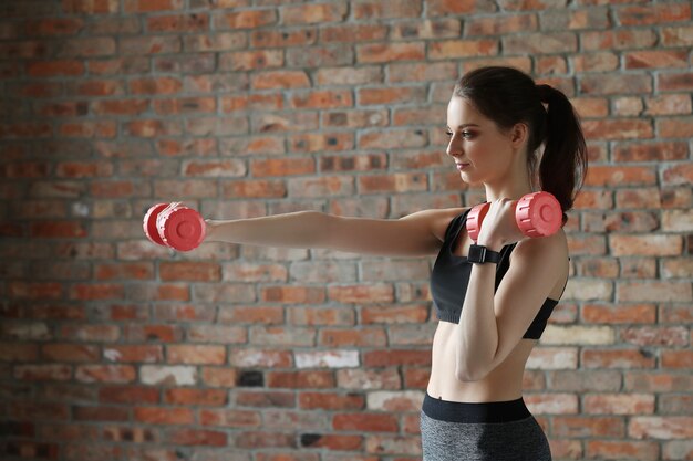 Young sportswoman with dumbbells