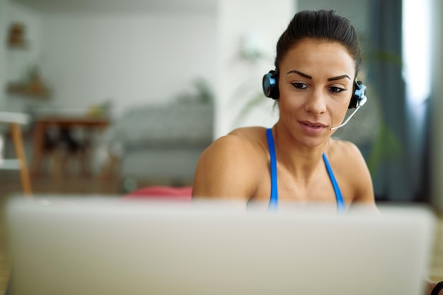 Free photo young sportswoman with headset using computer in the living room