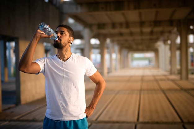 ハードトレーニング後に水を飲む若いスポーティなアスリート