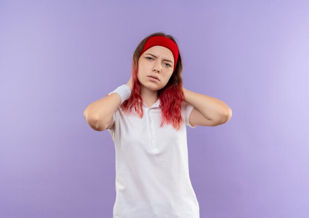 Young sporty girl with confident serious expression standing over purple wall