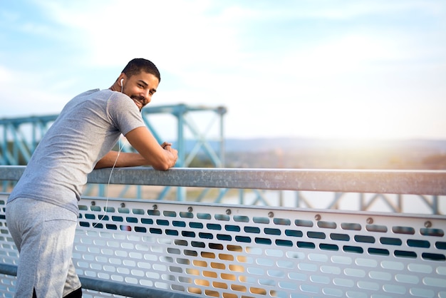 Young sporty man on the bridge having a break