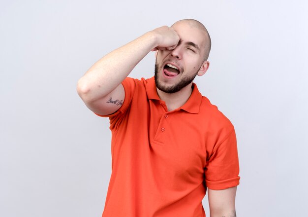 Young sporty man holding fist on eye isolated on white wall