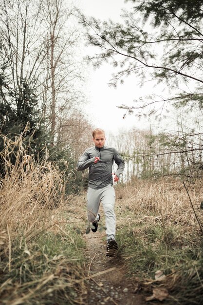 Free photo young sporty man running in forest