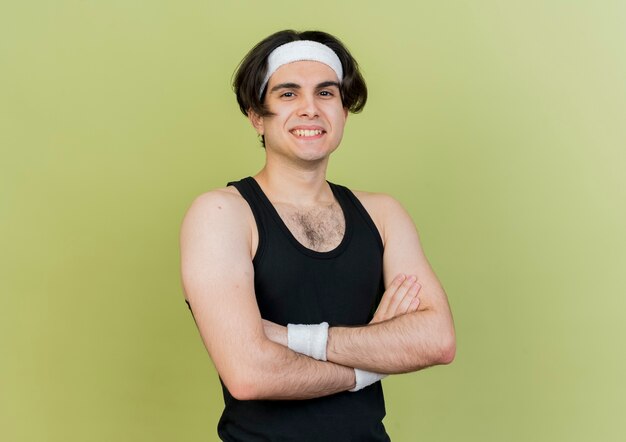 Young sporty man wearing sportswear and headband smiling confident with crossed arms on chest 