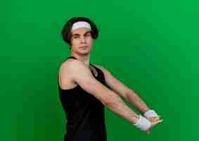 Free photo young sporty man wearing sportswear and headband stretching his hands