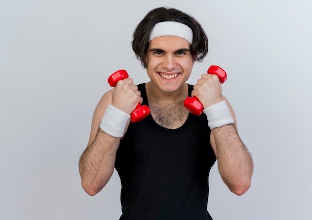 Young sporty man wearing sportswear and headband working out with dumbbells smiling with happy face 