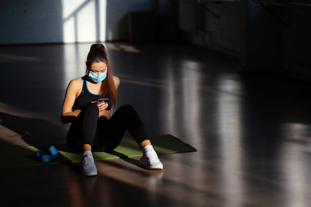 Young sporty woman after practicing yoga, break in doing exercise, relaxing on yoga mat