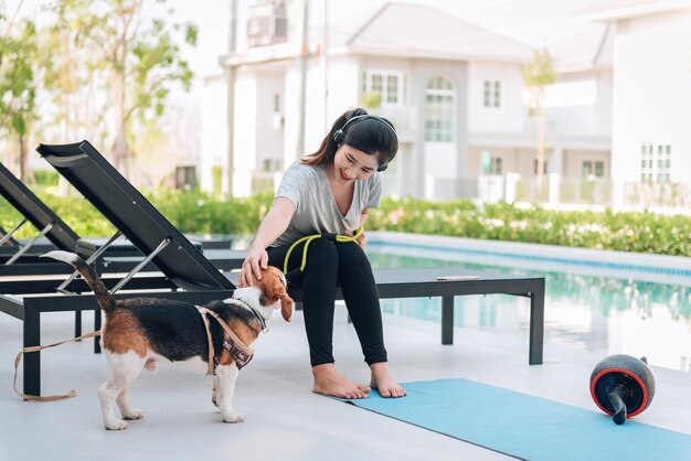 Молодая спортивная женщина играет со своей собакой бигль после тренировки дома