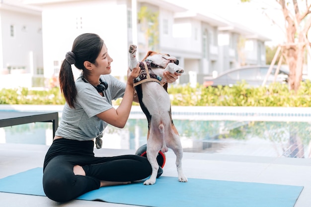 Giovane donna sportiva che gioca con il suo cane beagle dopo l'allenamento a casa