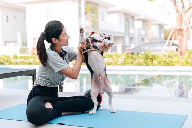 自宅でトレーニングした後、ビーグル犬と遊ぶ若いスポーティな女性