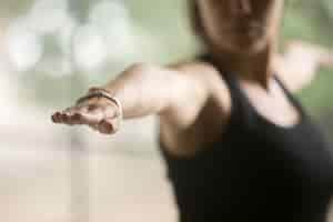 Free photo young sporty woman in warrior two pose, studio background