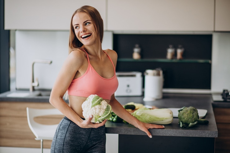 Free Photo young sporty woman with cauliflower at the kitchen