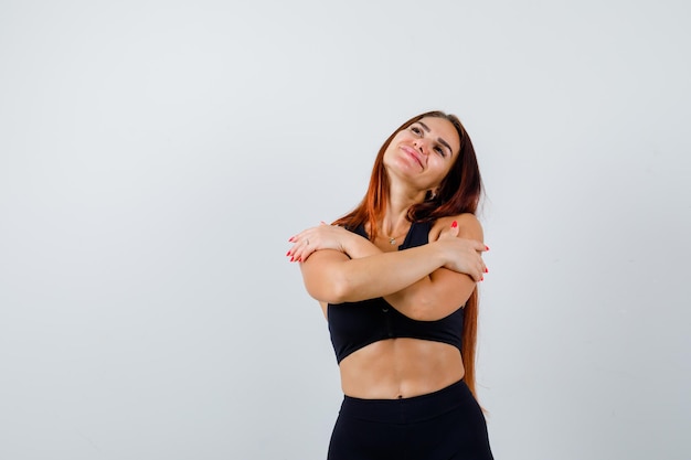 Giovane donna sportiva con i capelli lunghi in un top nero