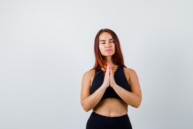 Young sporty woman with long hair praying