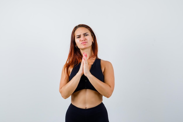 Young sporty woman with long hair praying