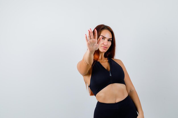 Young sporty woman with long hair showing stop gesture