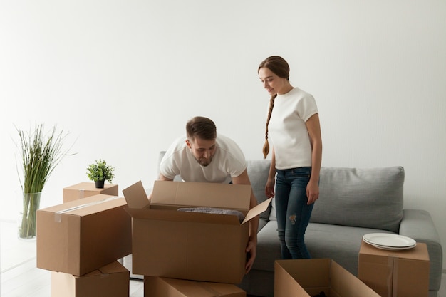 Молодые супруги с коробками переезжают в новую квартиру