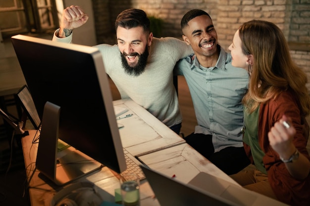 Free photo young startup team celebrating business success while using computer in the office