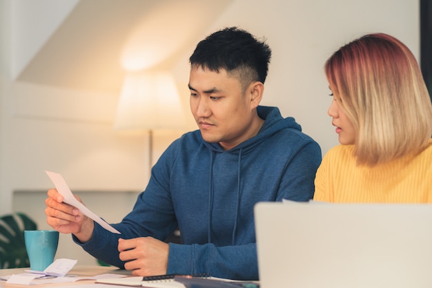 Free photo young stressed asian couple managing finances, reviewing their bank accounts using laptop computer