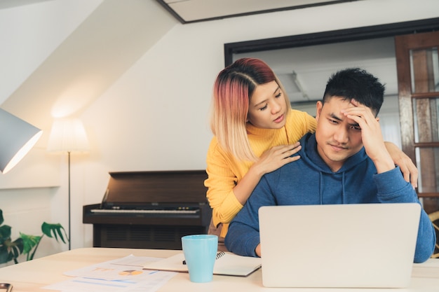 Free photo young stressed asian couple managing finances, reviewing their bank accounts using laptop computer