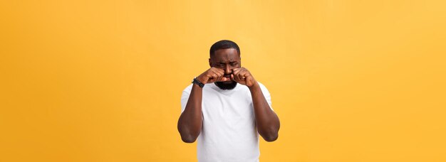 Young stressed man with hand on his face showing sadness and despair isolated over yellow background