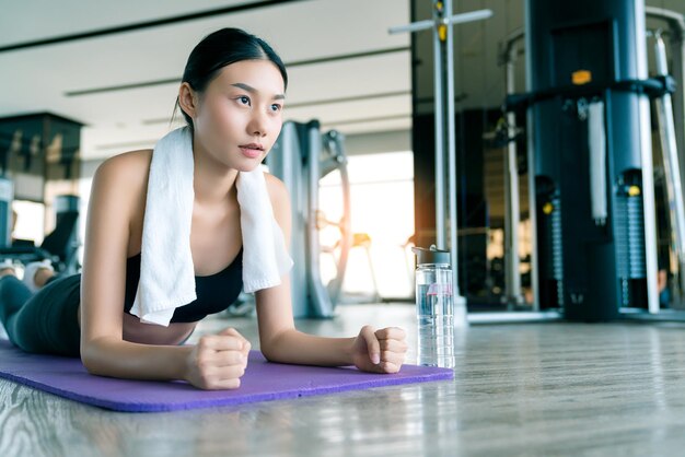 Young strong asian woman wirkout exercise doing plank in gym fitness background