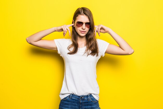 Young strong lady in white t-shirt and blue jeans stay in front of yellow studio background