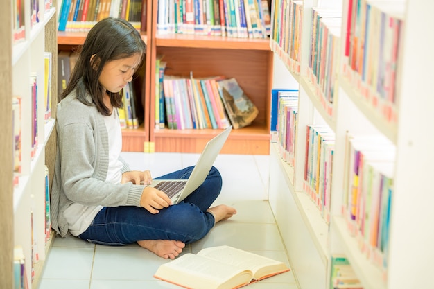 Молодая девушка студент сидит в библиотеке