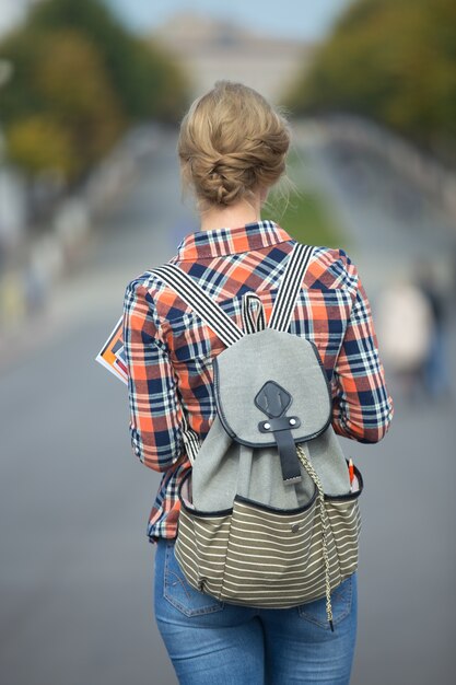Young student girl walking down the street with a backpack
