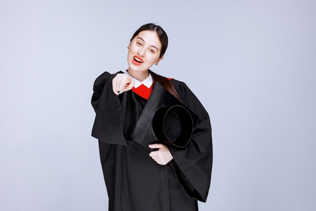 Young student in gown holding cap and posing. High quality photo