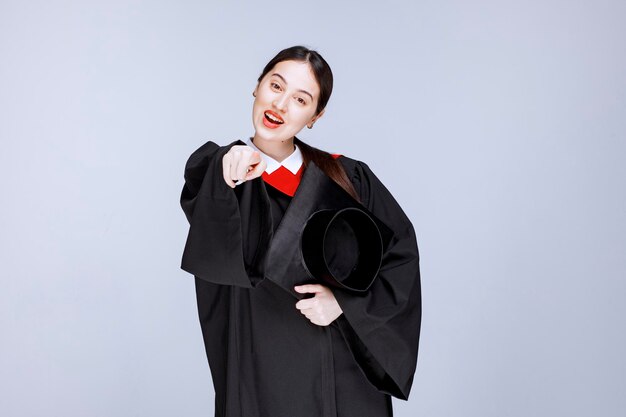 Young student in gown holding cap and posing. High quality photo