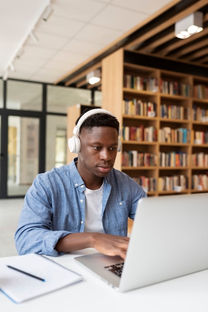 Foto gratuita giovane studente che impara in biblioteca