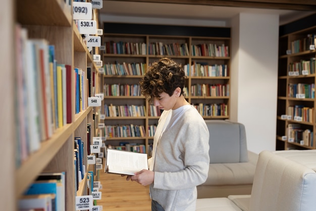 Foto gratuita giovane studente che impara in biblioteca