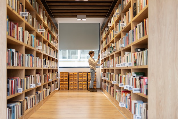 Free photo young student looking for a book in the library